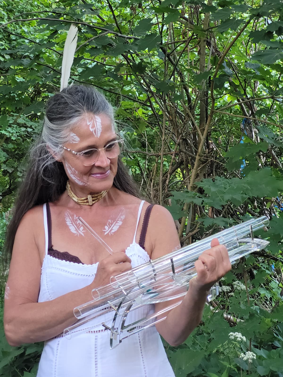 Antara Gisela Eßer spielt ein Kristallinstrument aus Bergkristall im Grünen
